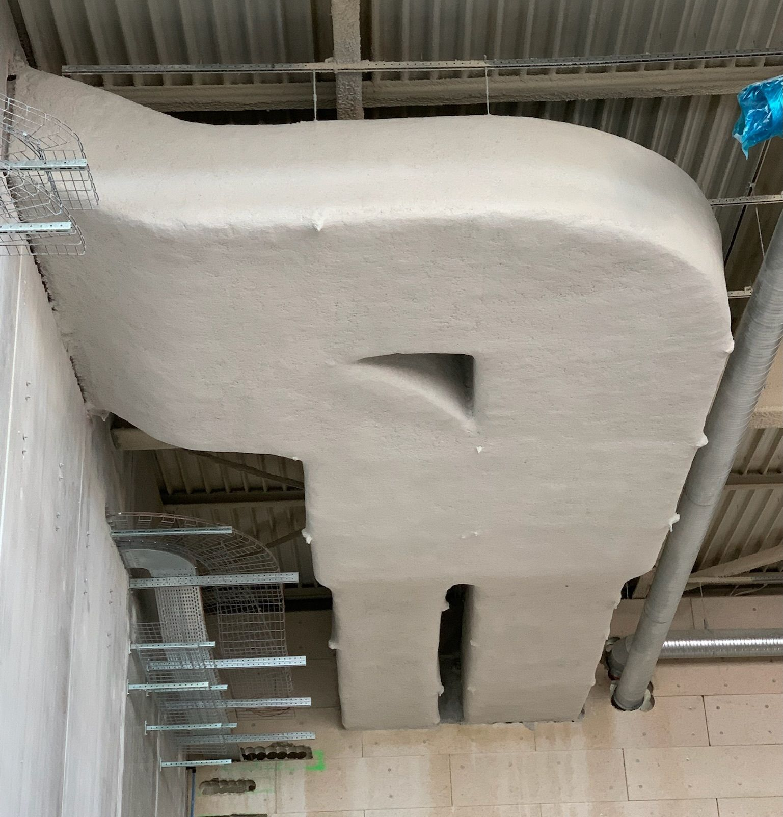 Conduits de CVC isolés contre un plafond avec des supports de fixation, gris clair, et une ouverture verticale étroite.