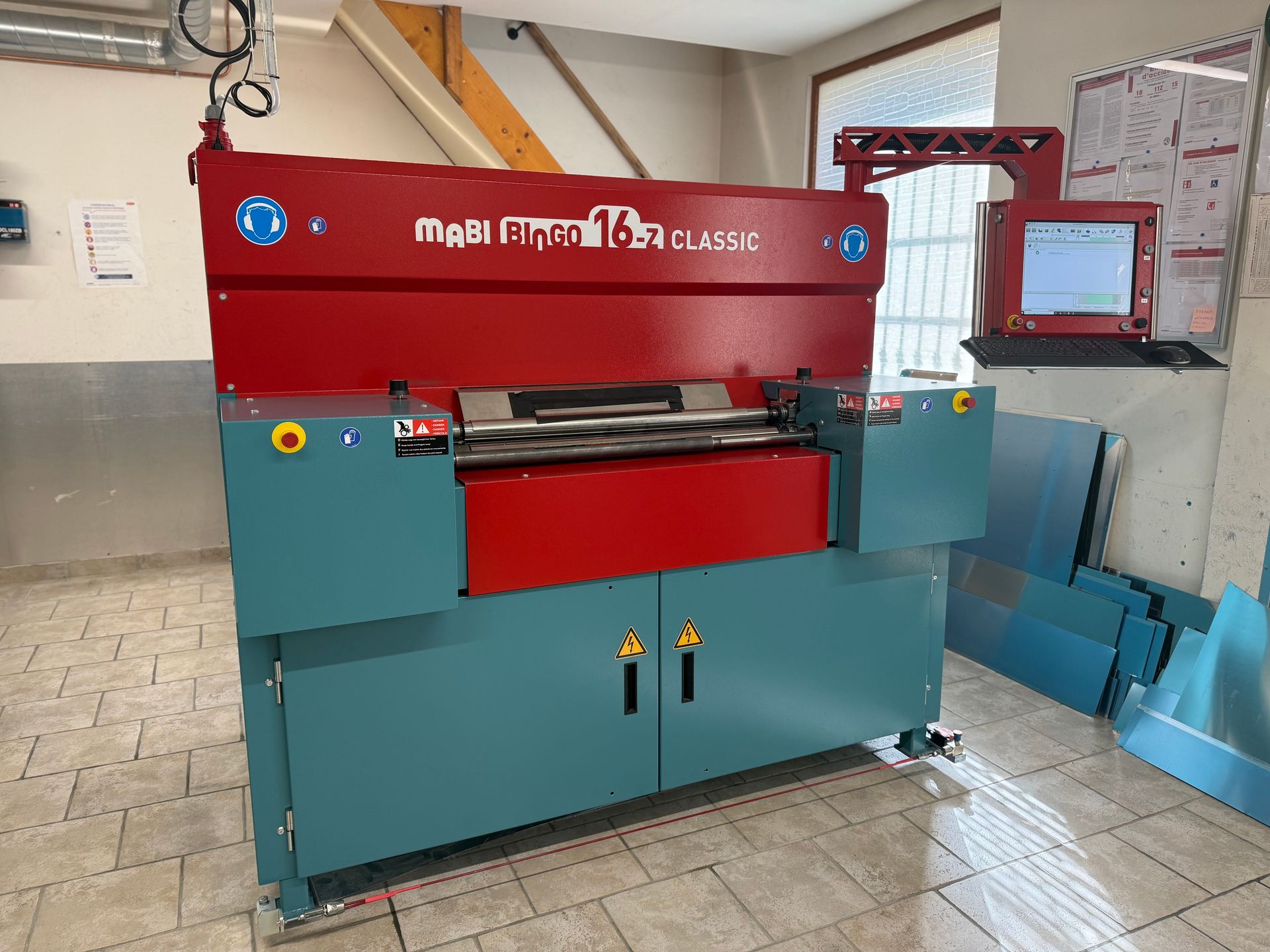 Plieuse de métal rouge et bleu sarcelle, MaBi, dans un atelier.
