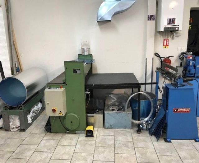 Atelier de métallurgie avec machines vertes et bleues, dont une rouleuse et une cintreuse de tubes.