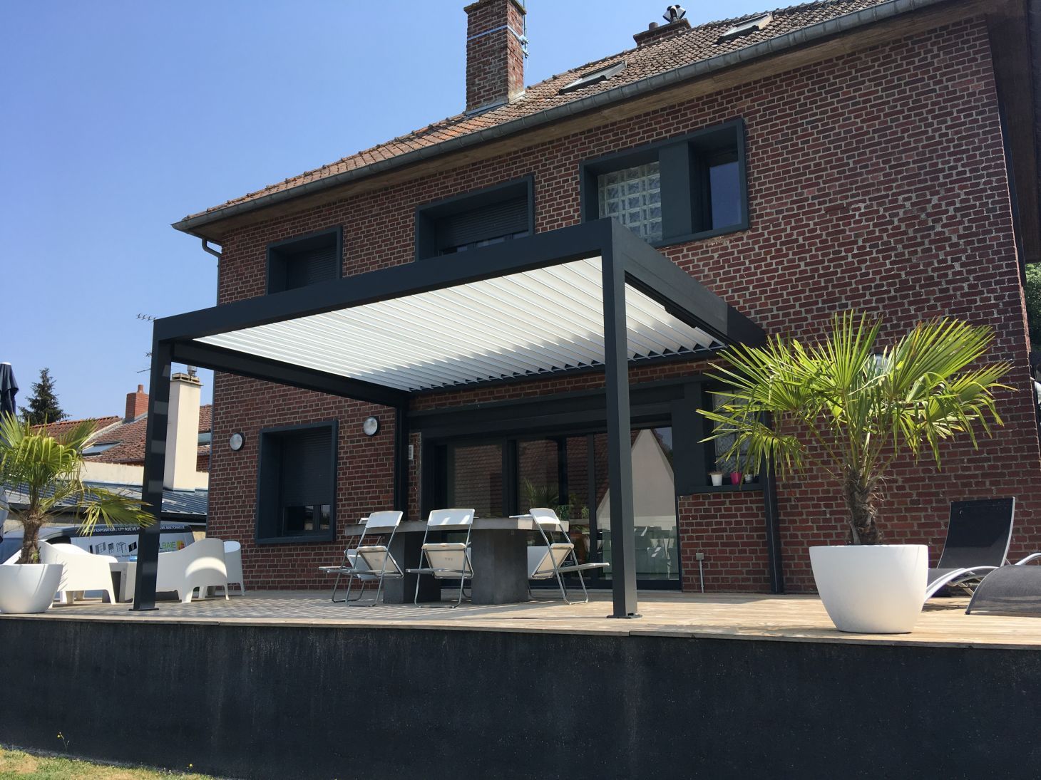 Une pergola devant une maison en brique rouge
