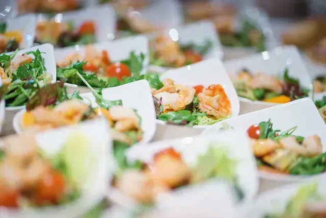 Una fila de platos de comida con camarones y verduras en una mesa.