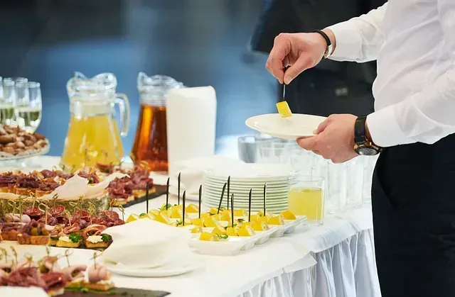 Un hombre está poniendo comida en un plato en una mesa de buffet.