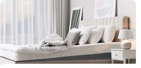 Un dormitorio con cama, mesita de noche, lámpara y cortinas.