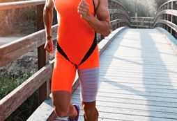 Un hombre con un traje naranja corre por un puente de madera.