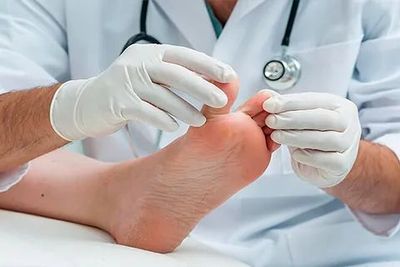 Un médico está examinando el pie de un paciente con un estetoscopio.