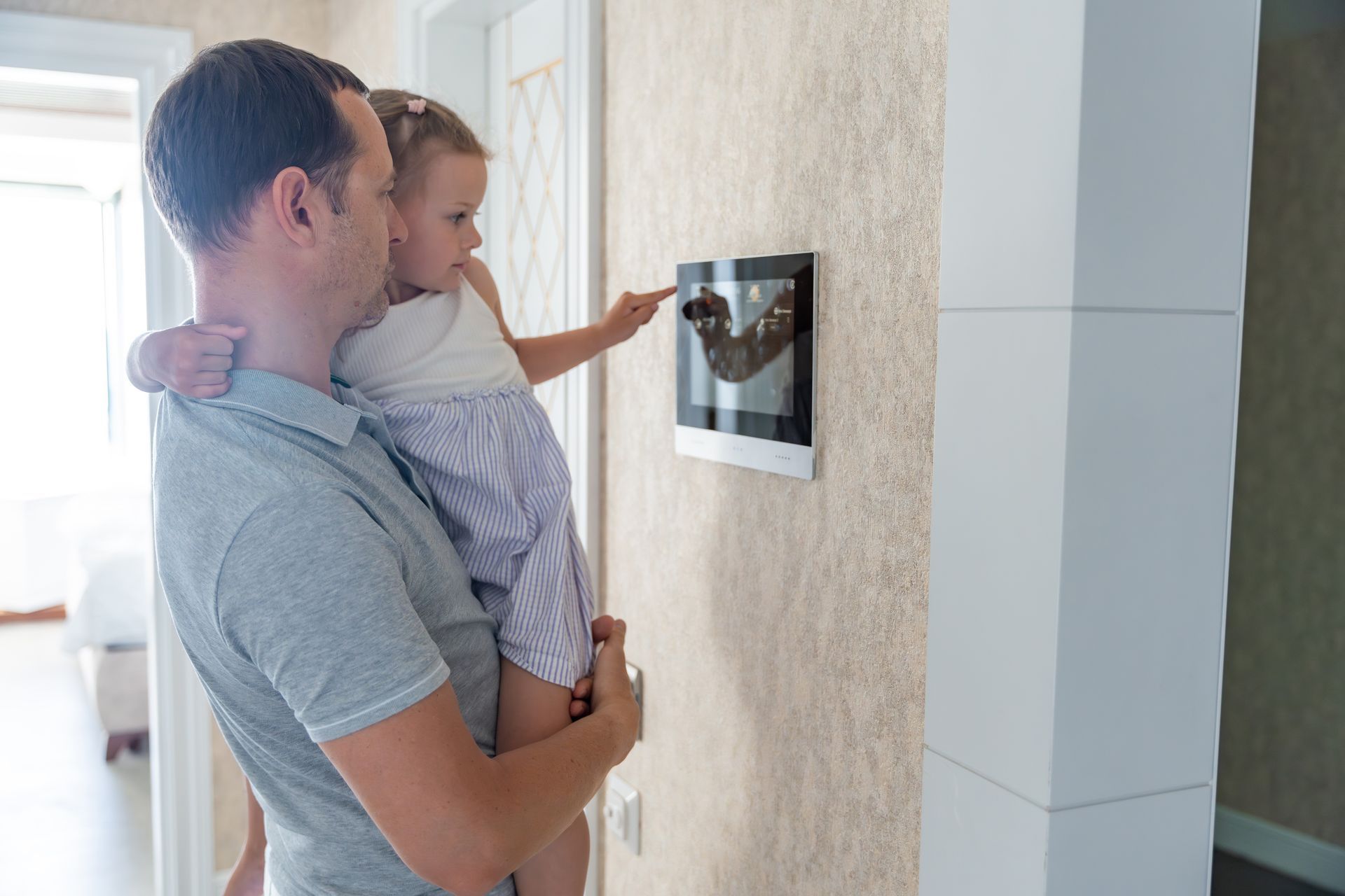 Un père et sa fille regardant le panneau de contrôle d'une alarme connectée