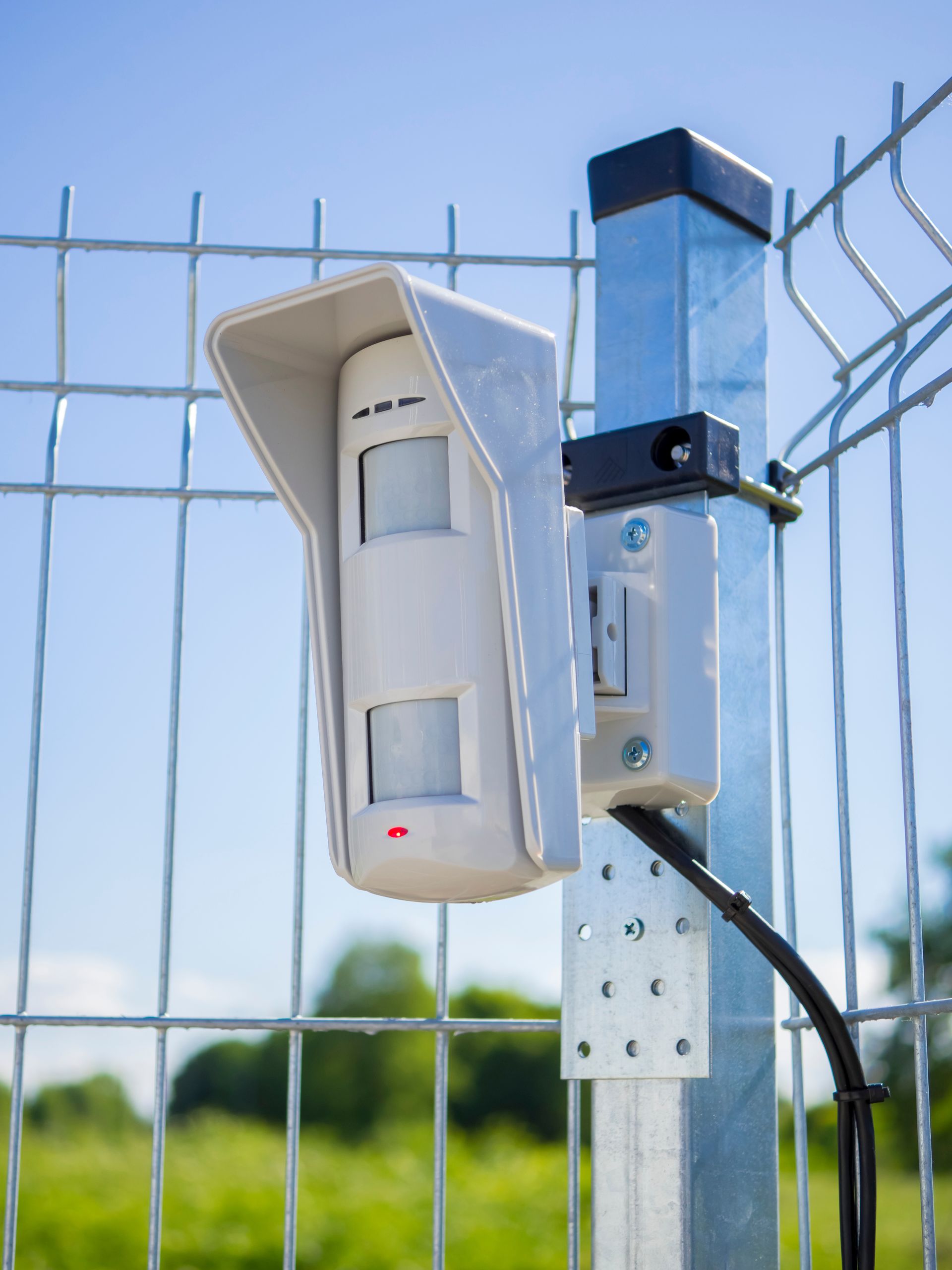 Détecteur de mouvement filaire installé sur une clôture extérieure