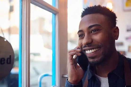 Hombre sonriente hablando por teléfono en una puerta iluminada