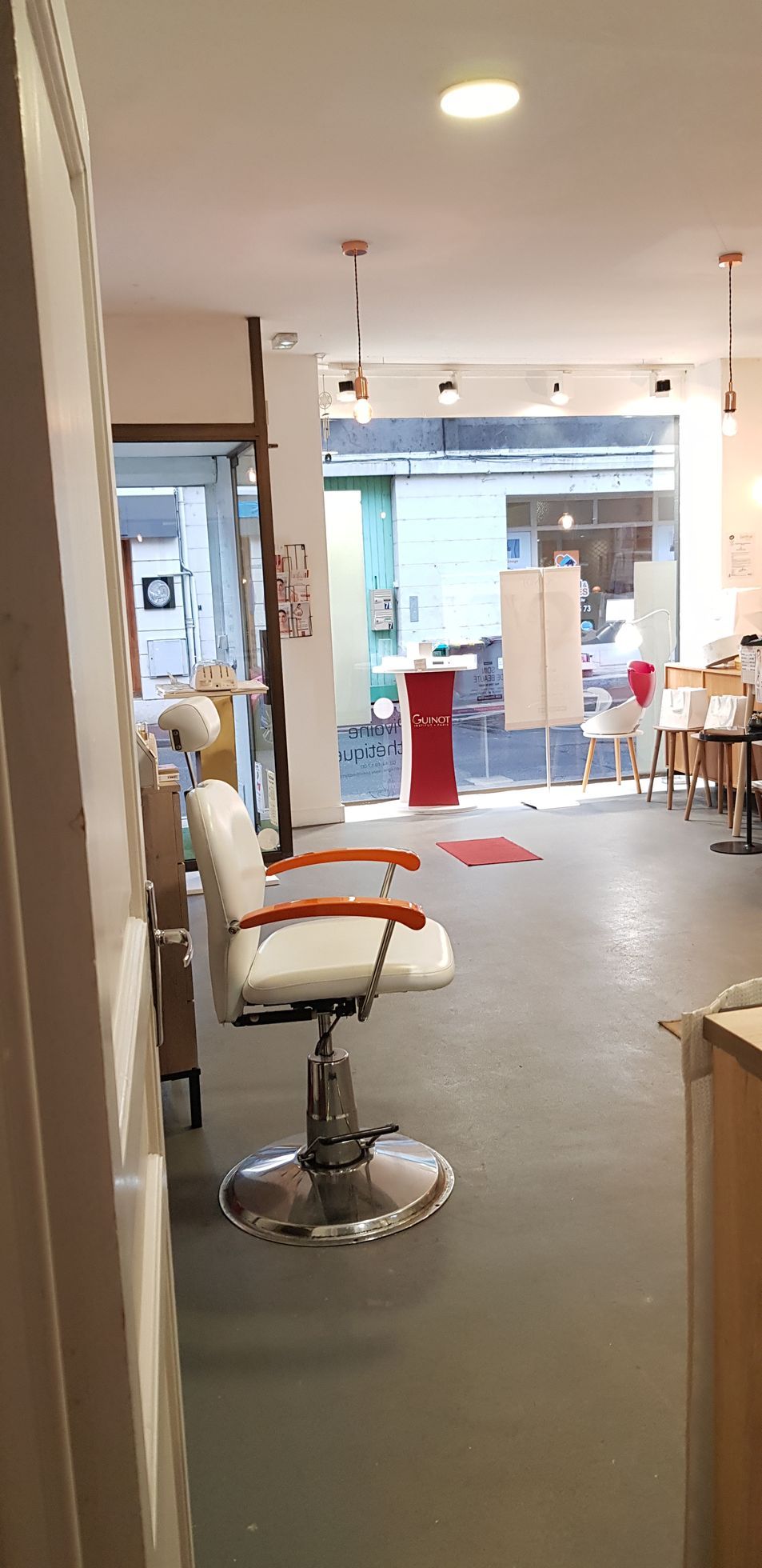 Fauteuil de soins blanc face à la vitrine dans un espace d’accueil lumineux d’institut de beauté