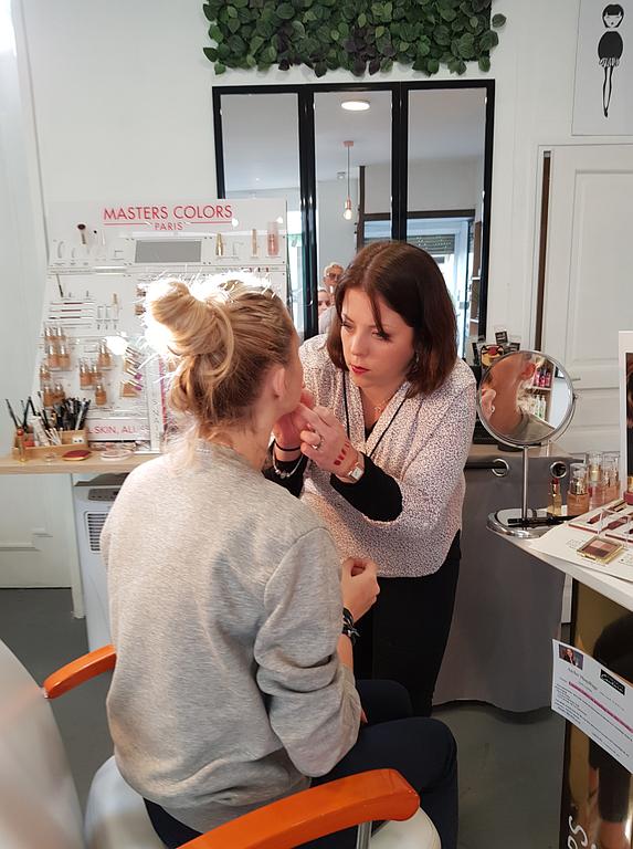 Maquilleuse appliquant du maquillage sur une cliente assise dans un institut