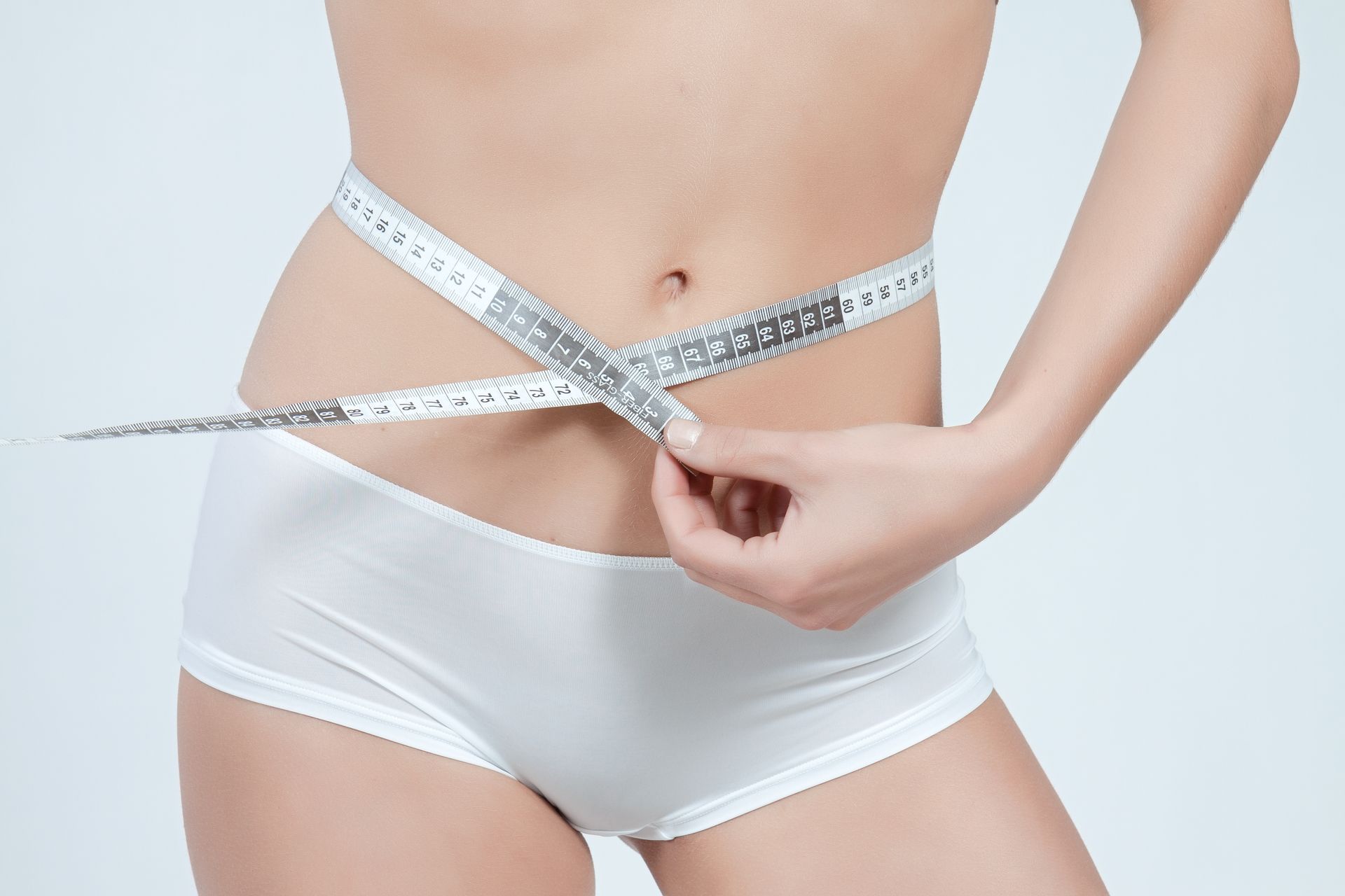 Un mètre ruban entourant l'abdomen d'une femme