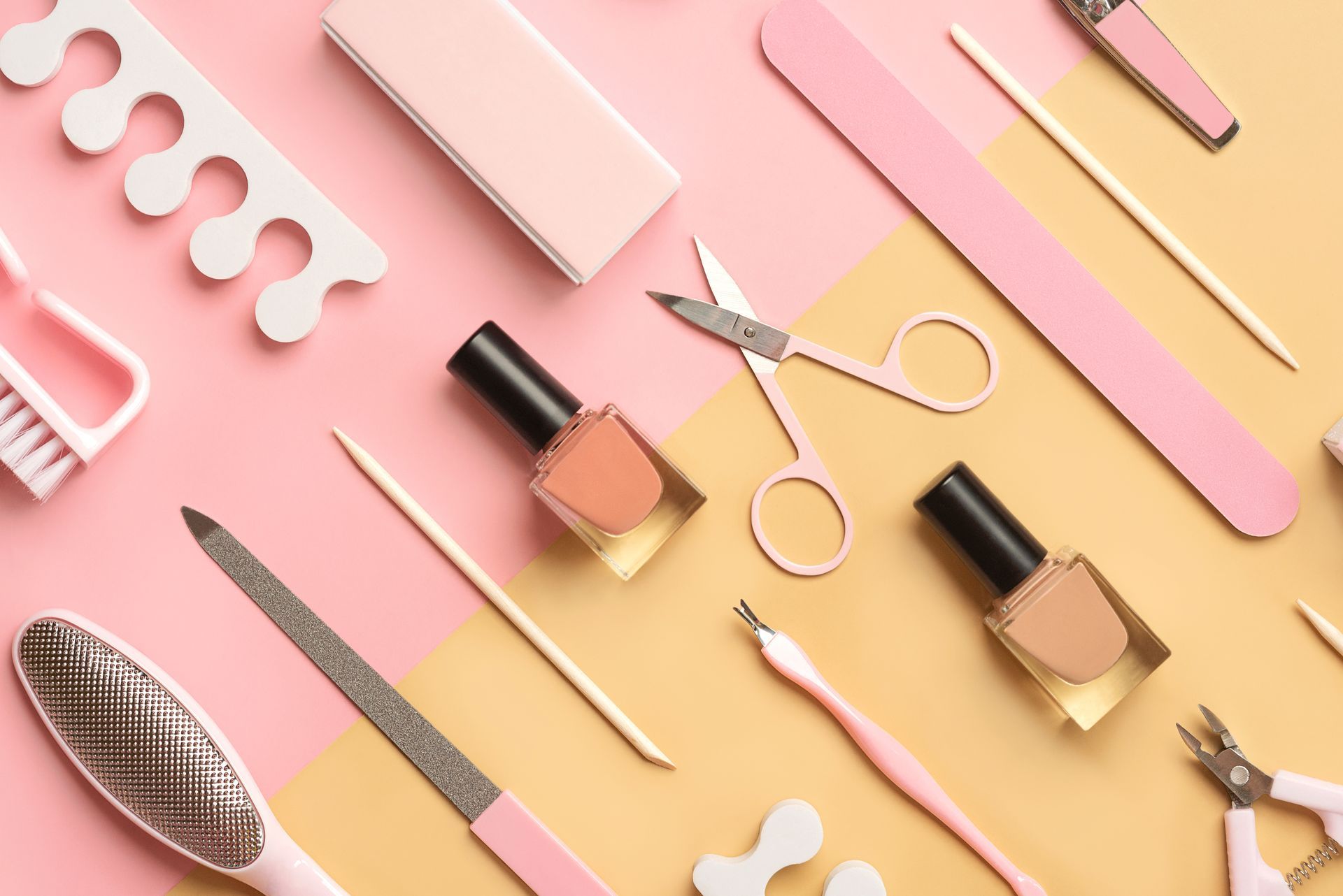 Outils de manucure et pédicure disposés sur fond rose et beige