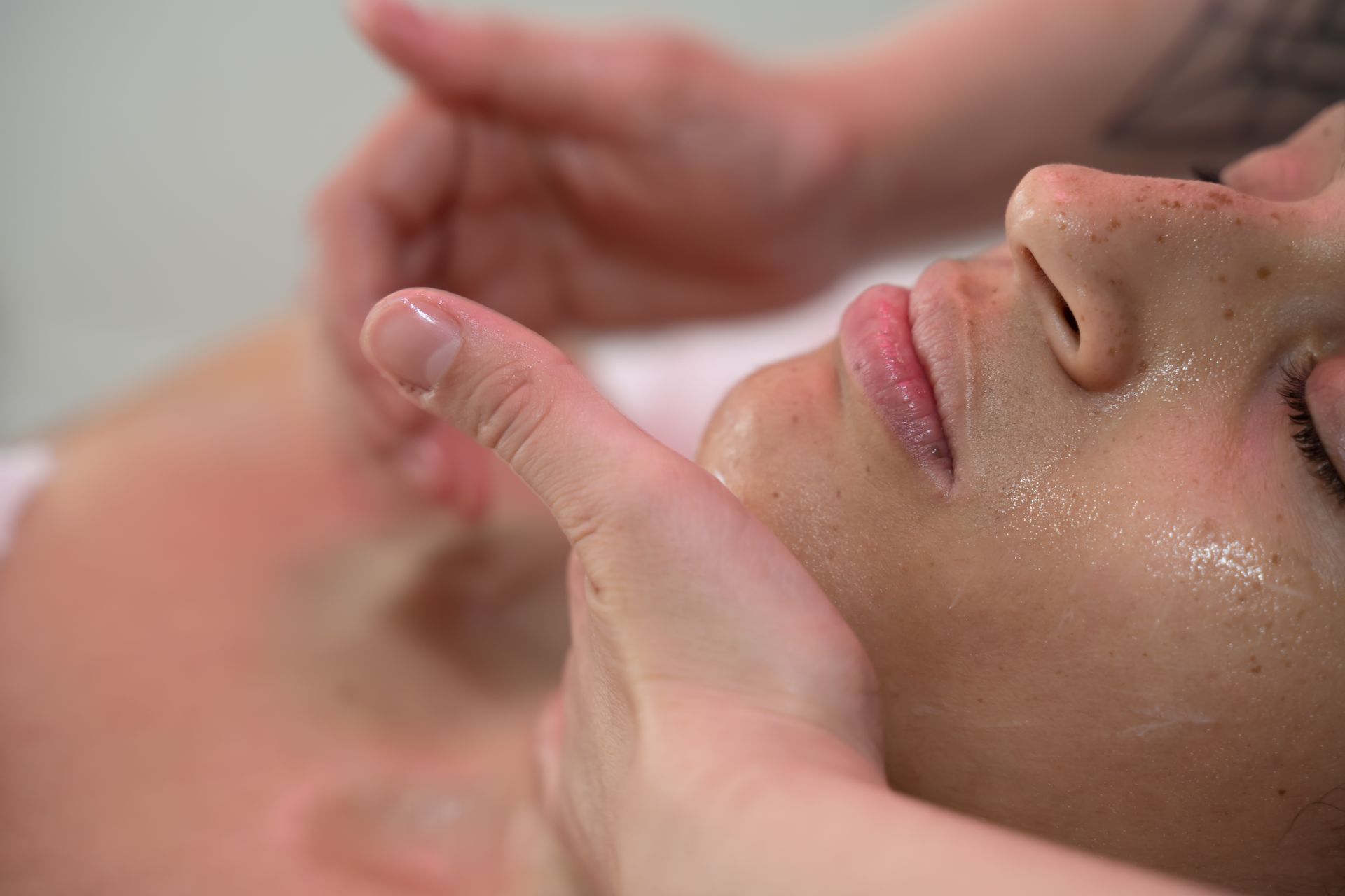 Deux mains effectuent un massage sur le visage d'une personne allongée