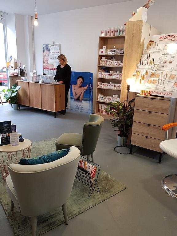 Accueil de l’institut de beauté avec fauteuils, comptoir en bois, étagères de produits cosmétiques