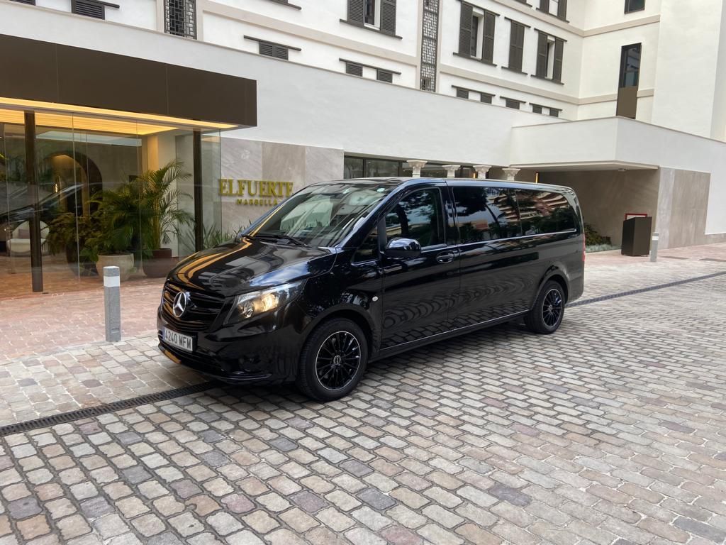 Una camioneta negra está estacionada en una calle adoquinada frente a un edificio.