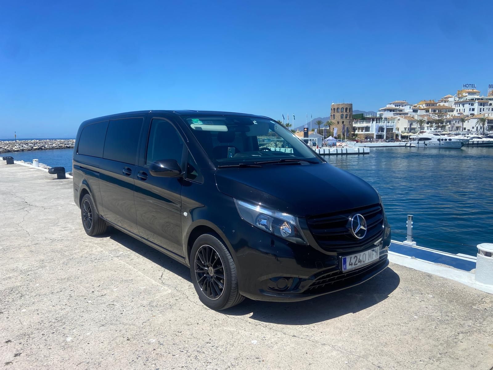 Una camioneta negra está estacionada al lado de un cuerpo de agua.