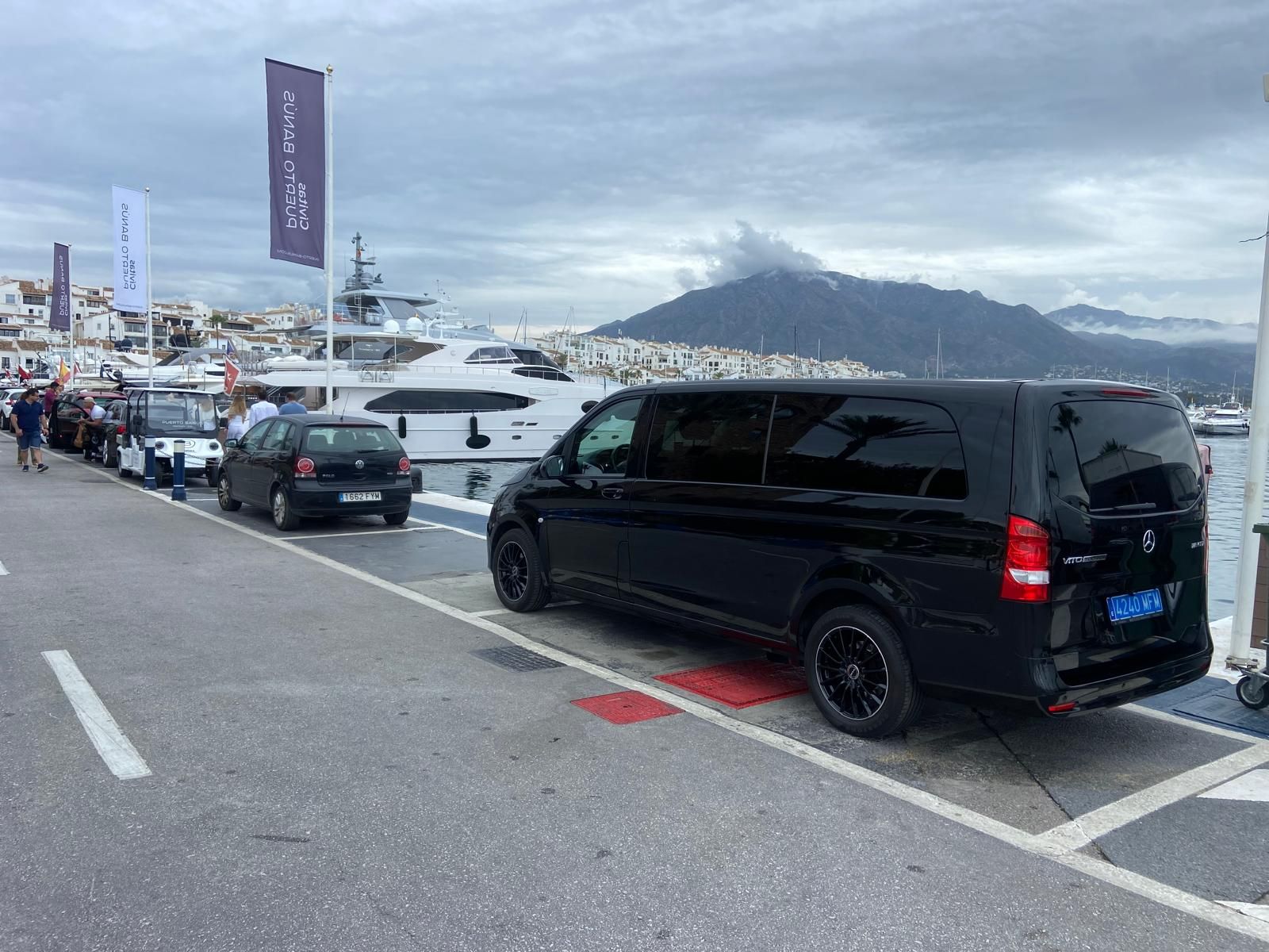 Una camioneta negra está estacionada en un estacionamiento al lado de un barco.