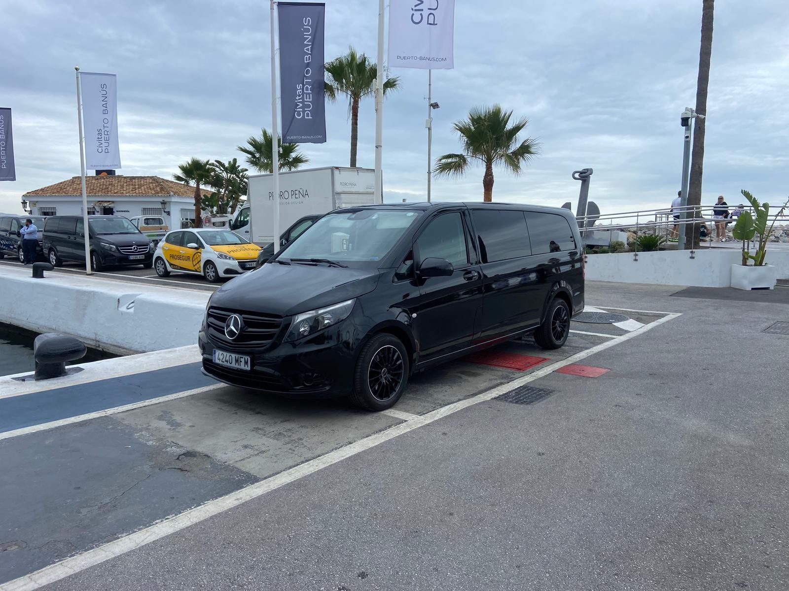 Una camioneta negra está estacionada en un estacionamiento al lado de un muelle.