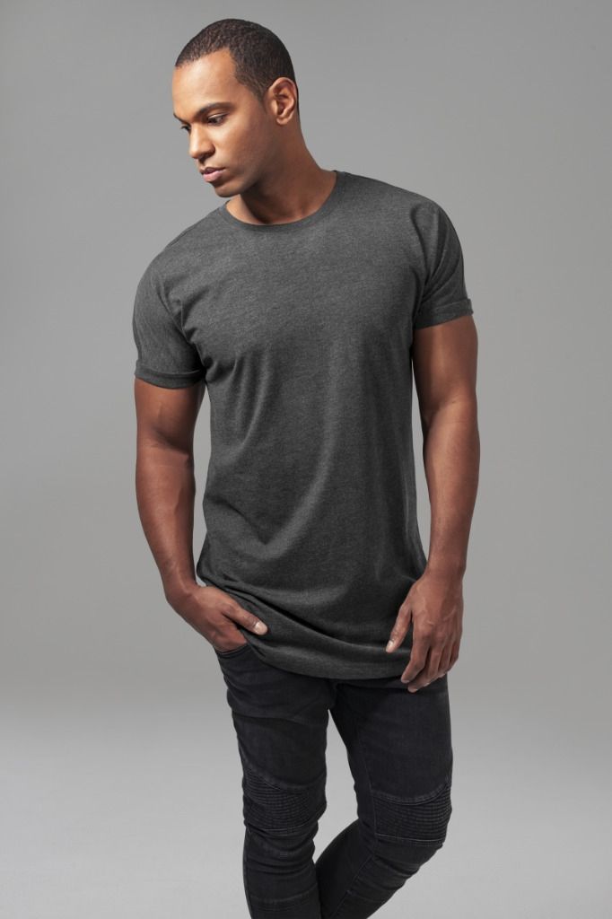 Mies tummanharmaassa t-paidassa ja farkuissa, kädet taskuissa, katsoo alas.