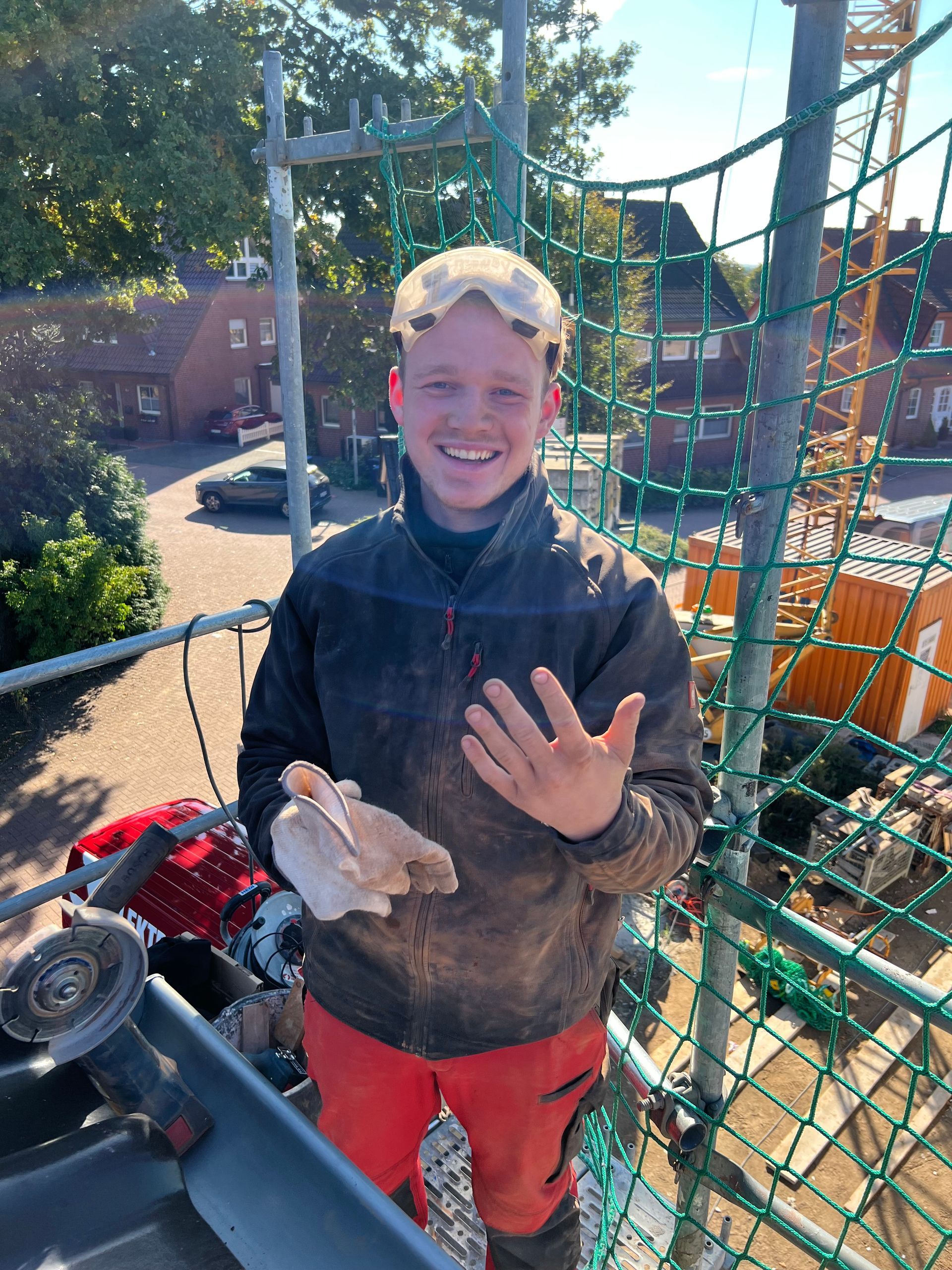 Ein lächelnder Arbeiter in schlammiger Kleidung hält eine weiße Ratte auf einem sonnigen Outdoor-Abenteuerkurs.