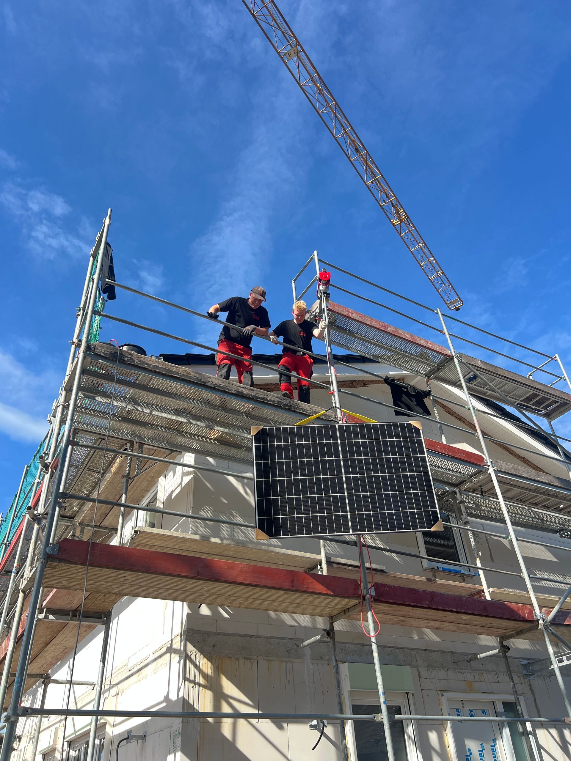 Arbeiter auf einem Gerüst montieren unter blauem Himmel ein Dachgerüst an einem Haus