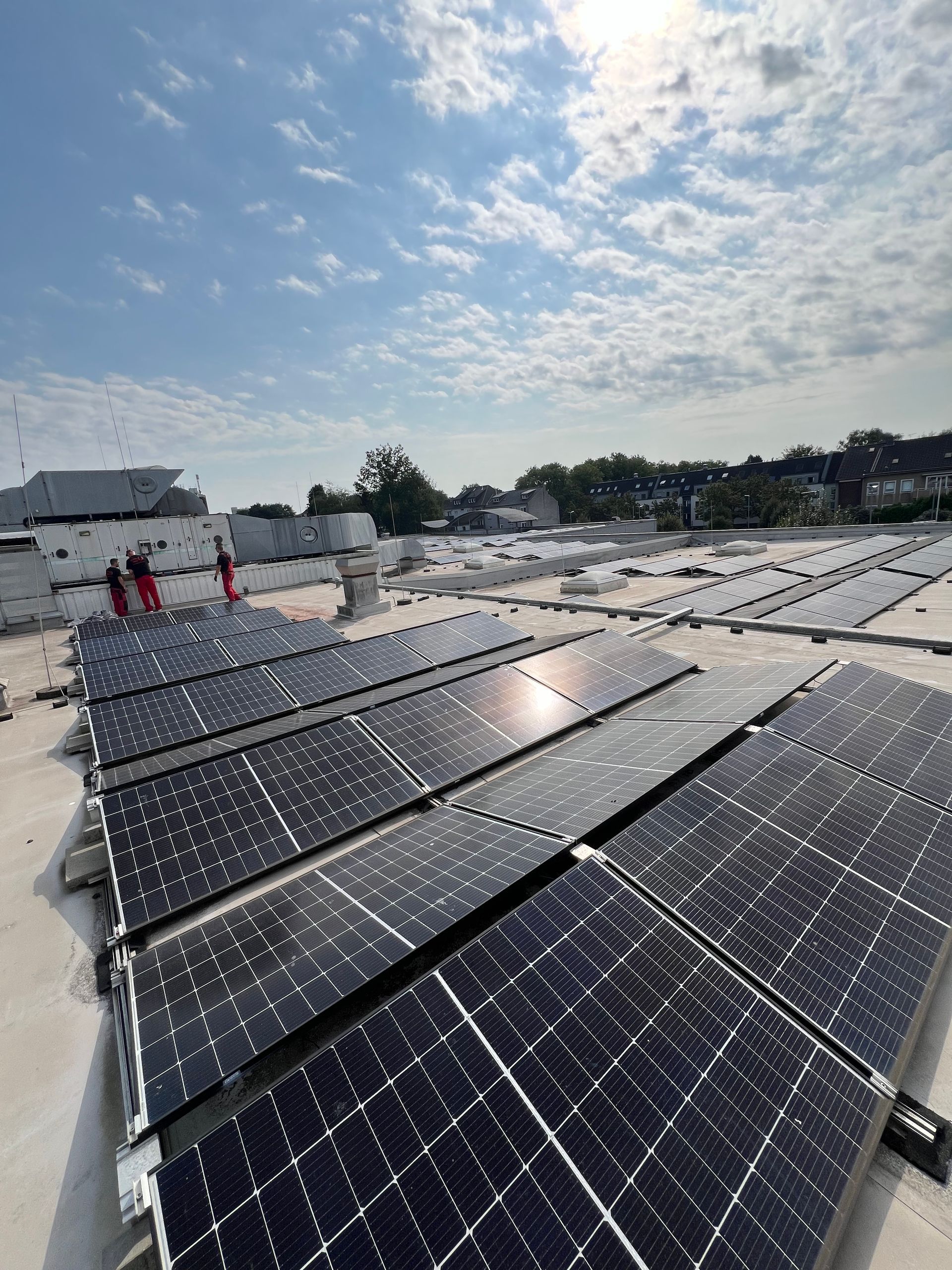 Solarpaneele bedecken ein Dach unter einem hellen, teilweise bewölkten Himmel