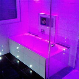 Lilafarbene indirekte Beleuchtung um eine Badewanne