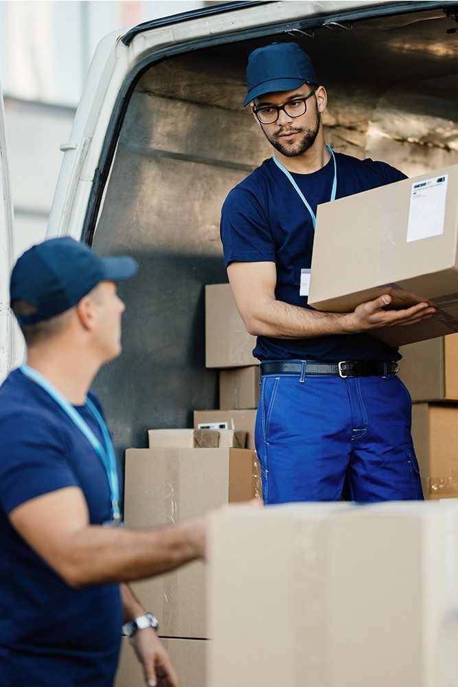 Trabajadores de almacén descargando cajas de cartón de un camión de reparto