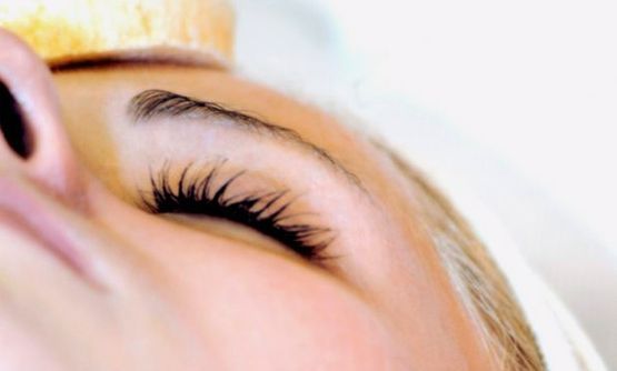 Primer plano de un ojo cerrado con largas pestañas y una mano apoyada en la frente.