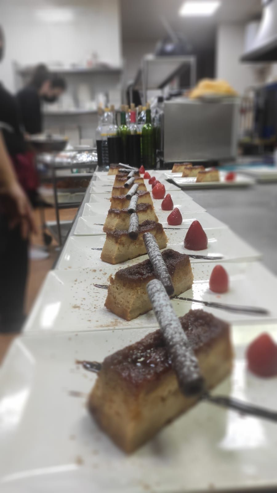 Una fila de postres están alineados en platos en una cocina.