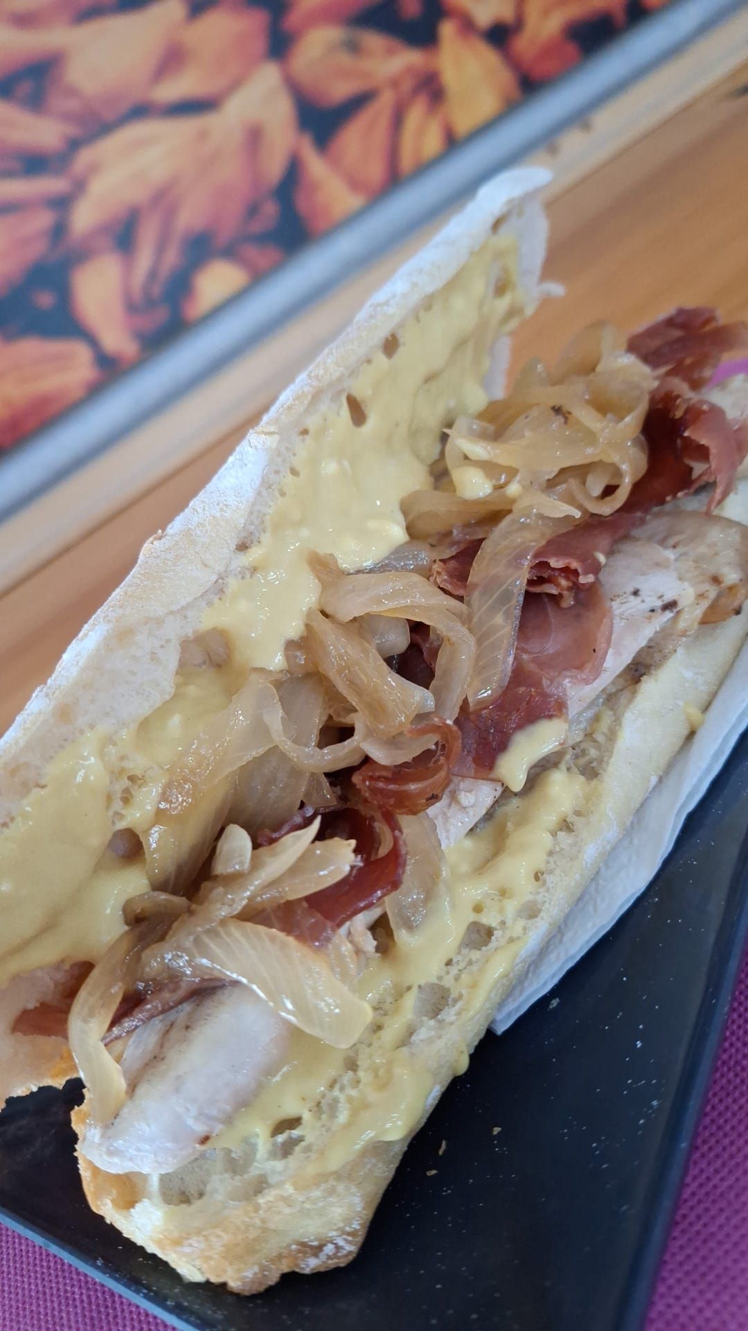 Un primer plano de un sándwich en un plato con papas fritas en el fondo.