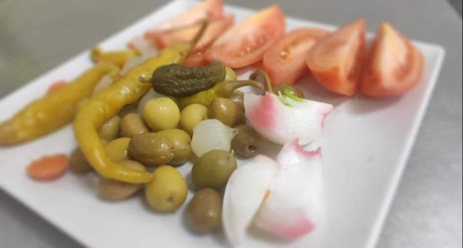 Un plato blanco cubierto de pepinillos y tomates sobre una mesa.