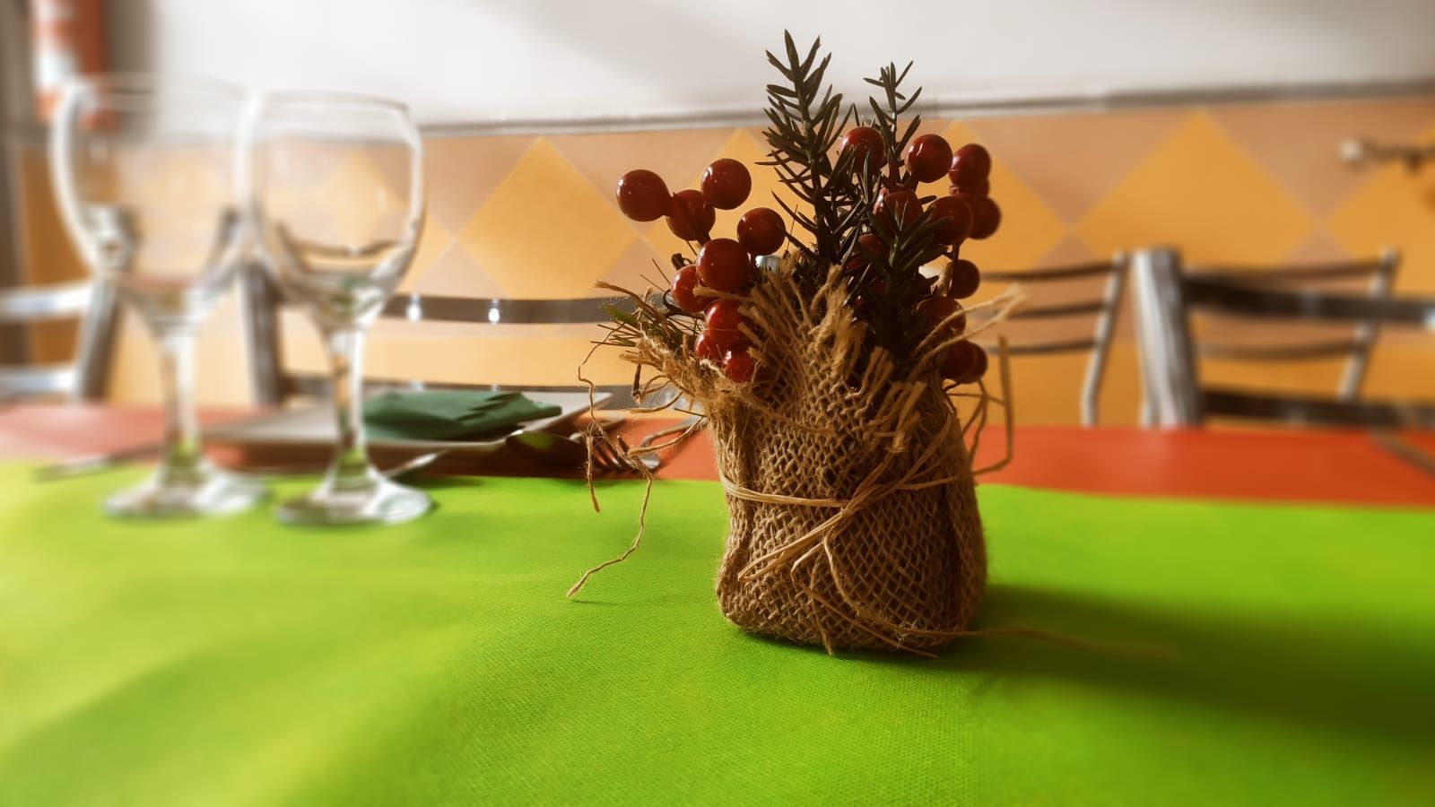 Un mantel verde con un jarrón de flores encima.