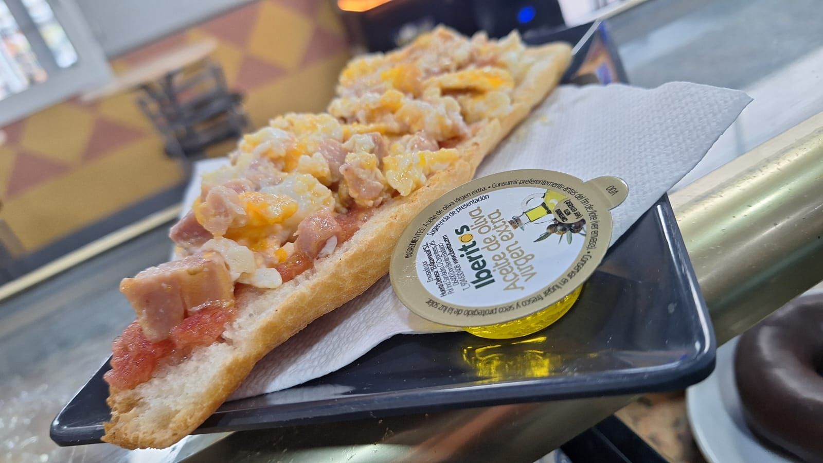 Un primer plano de un sándwich en un plato con un recipiente con miel encima.