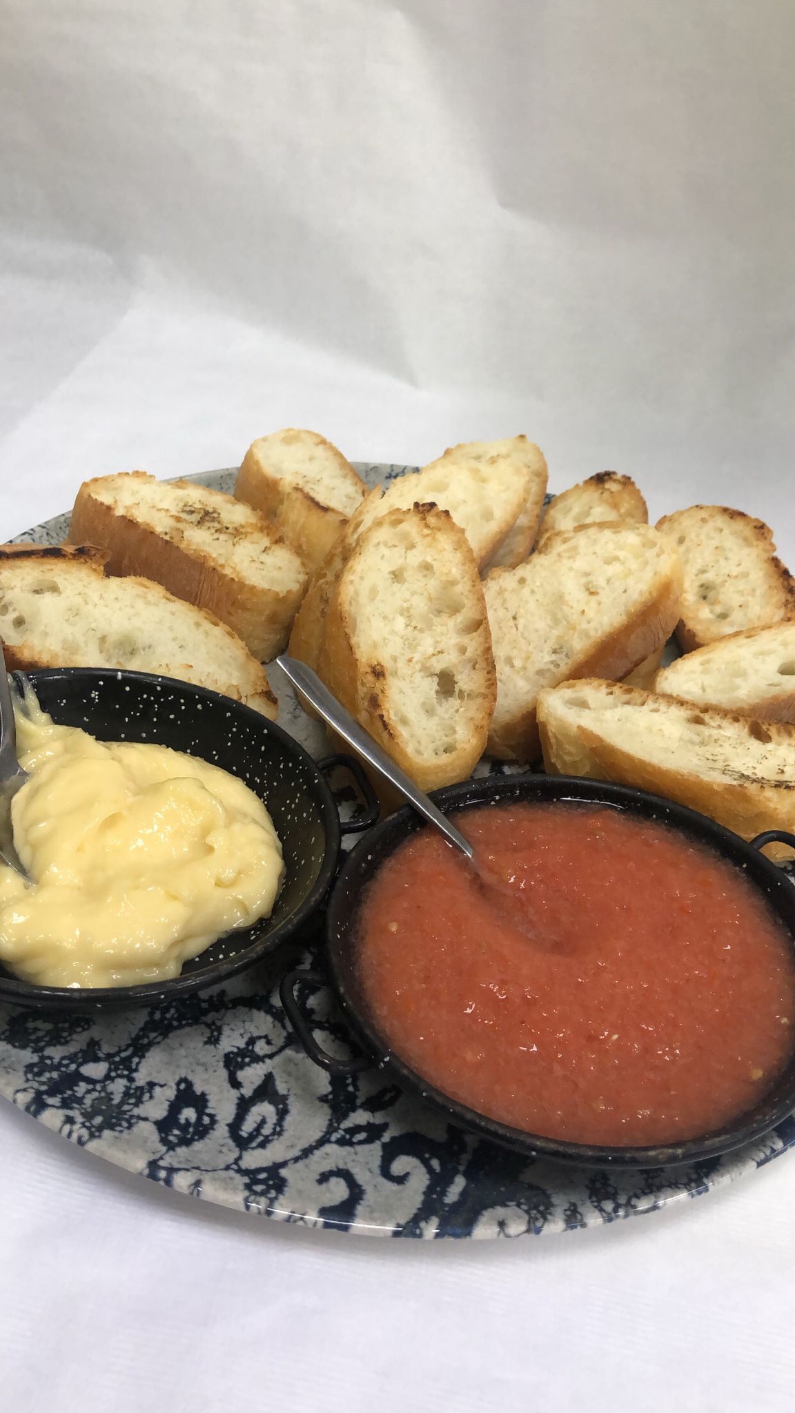 Un plato de comida con pan y salsas sobre una mesa.