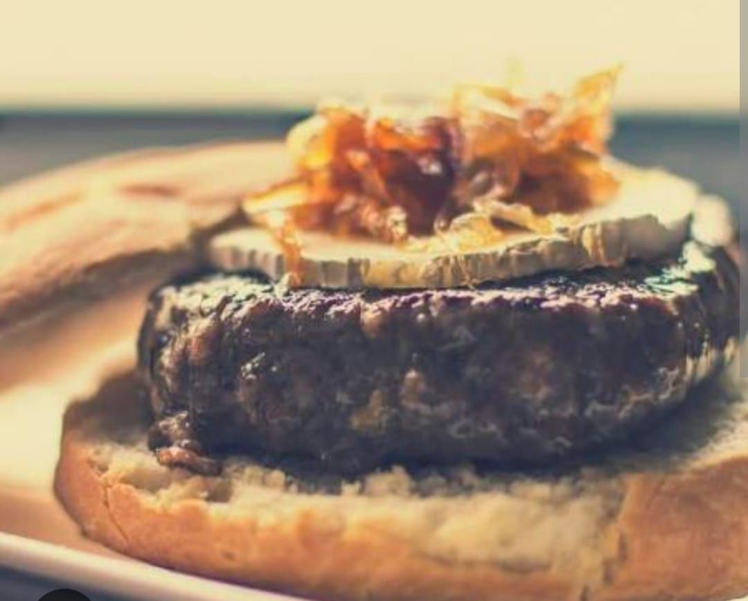 Un primer plano de una hamburguesa en un pan sobre un plato.