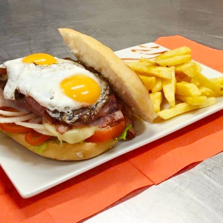 Un plato blanco cubierto con un sándwich y papas fritas.