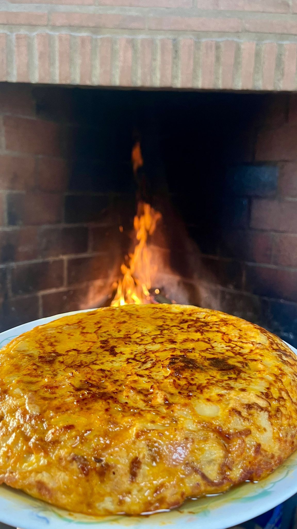 Un pastel está sentado en un plato frente a una chimenea.