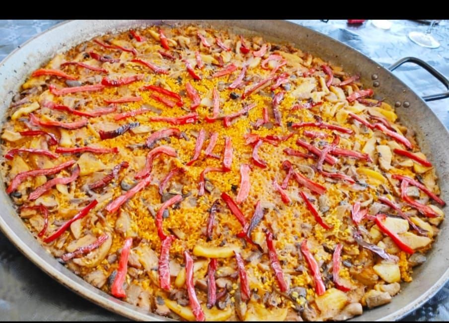 Una sartén grande llena de arroz, champiñones y pimientos rojos.