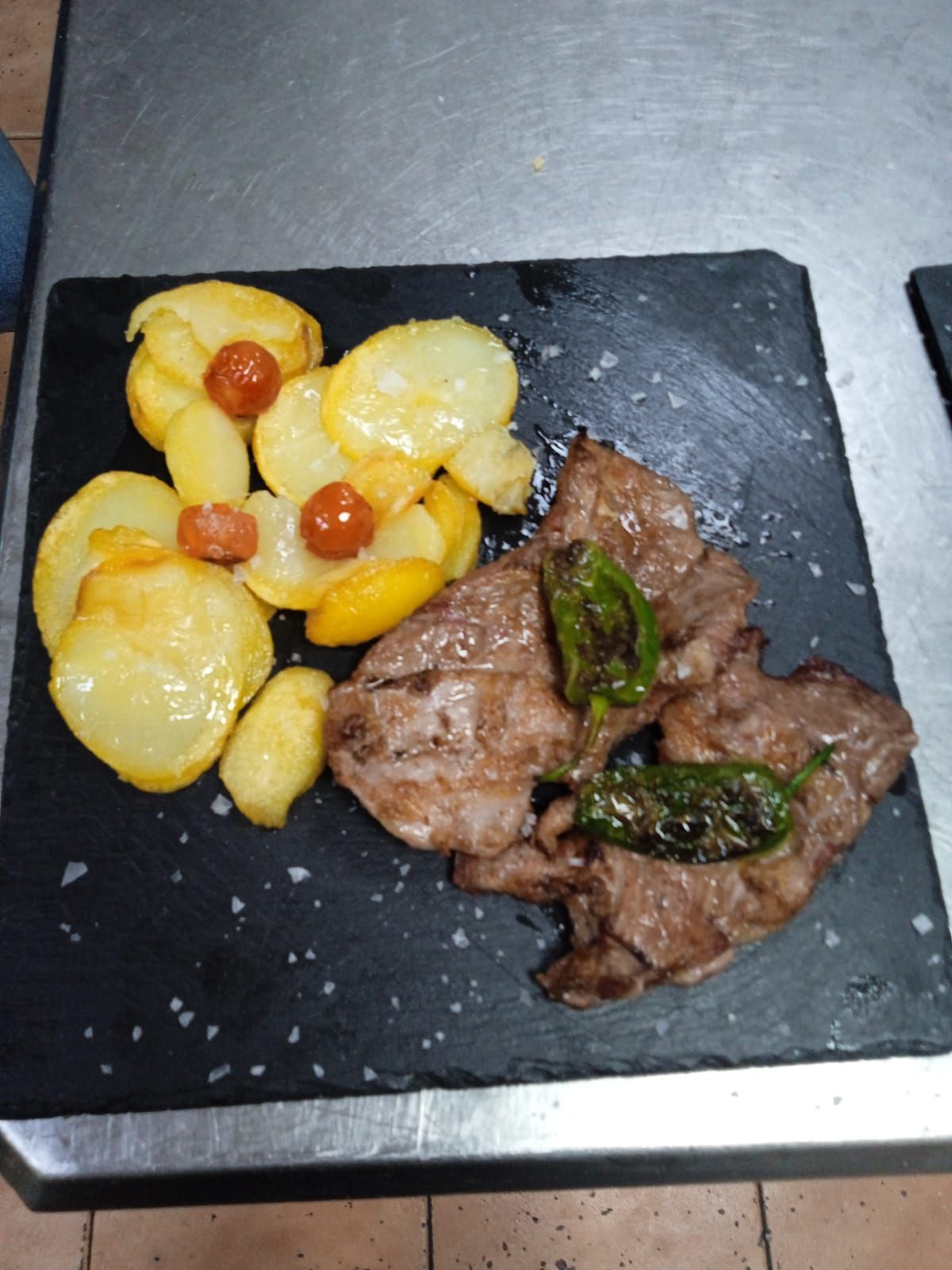 Un plato de comida con carne y patatas en una mesa.