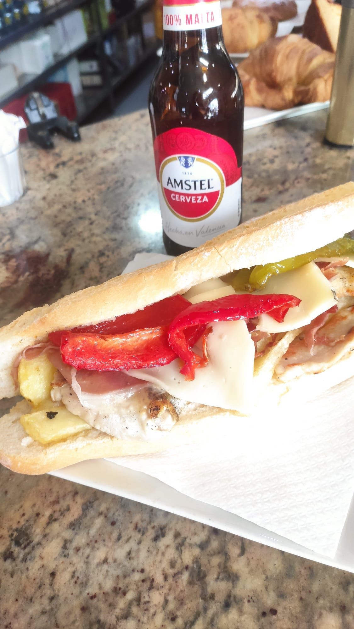 Un sándwich está en un plato al lado de una botella de cerveza.
