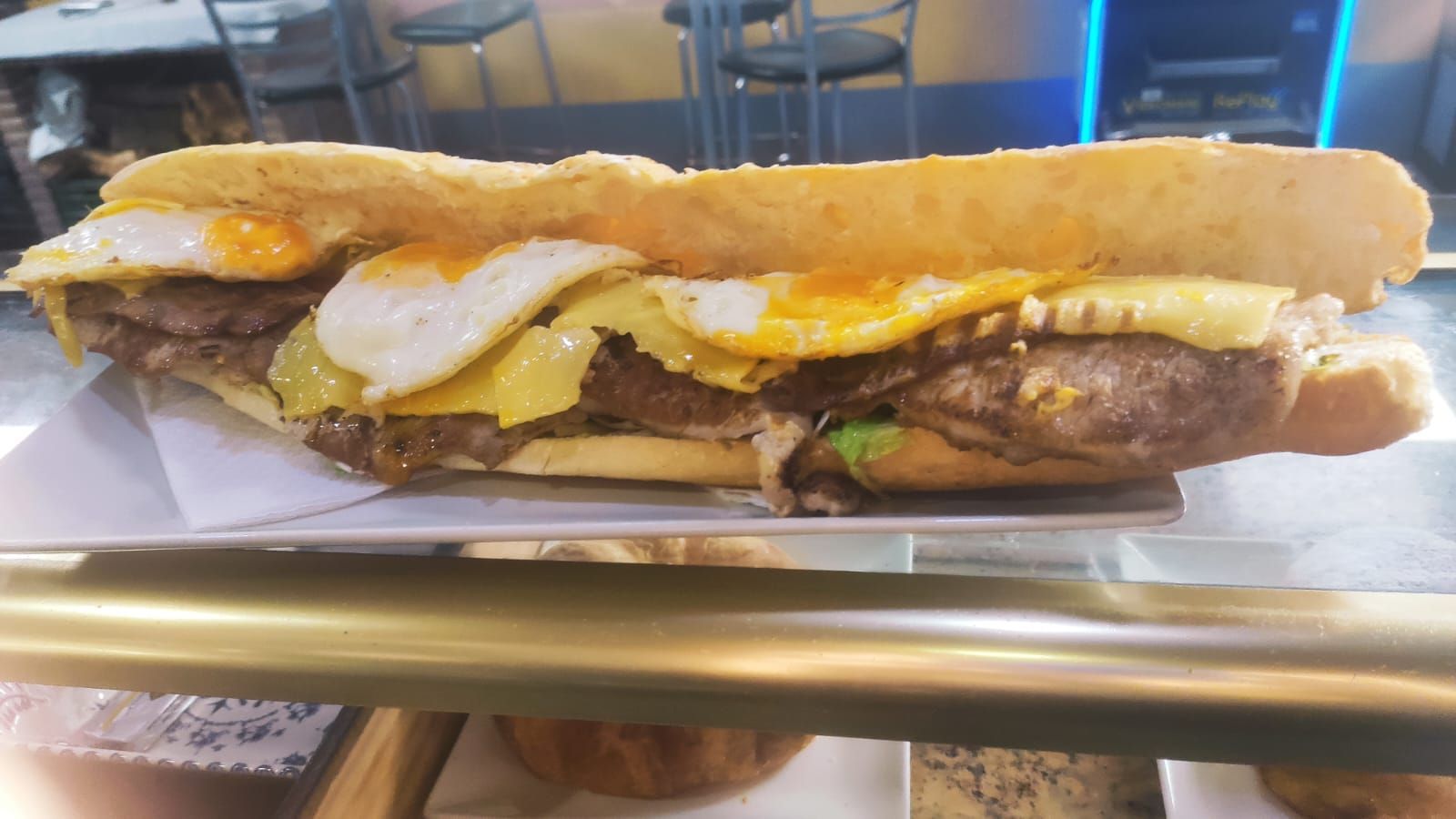 En una vitrina hay un sándwich con carne y huevos.