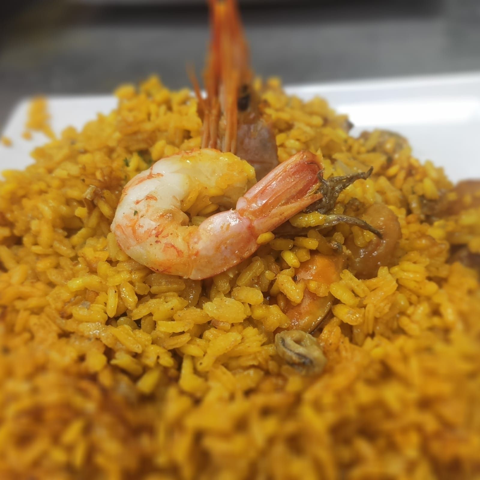Un primer plano de un plato de arroz con camarones encima.