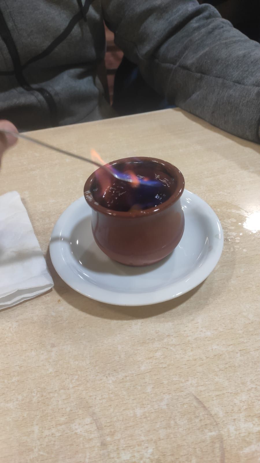 Una taza de café con una cuchara dentro está sobre un platillo sobre una mesa.