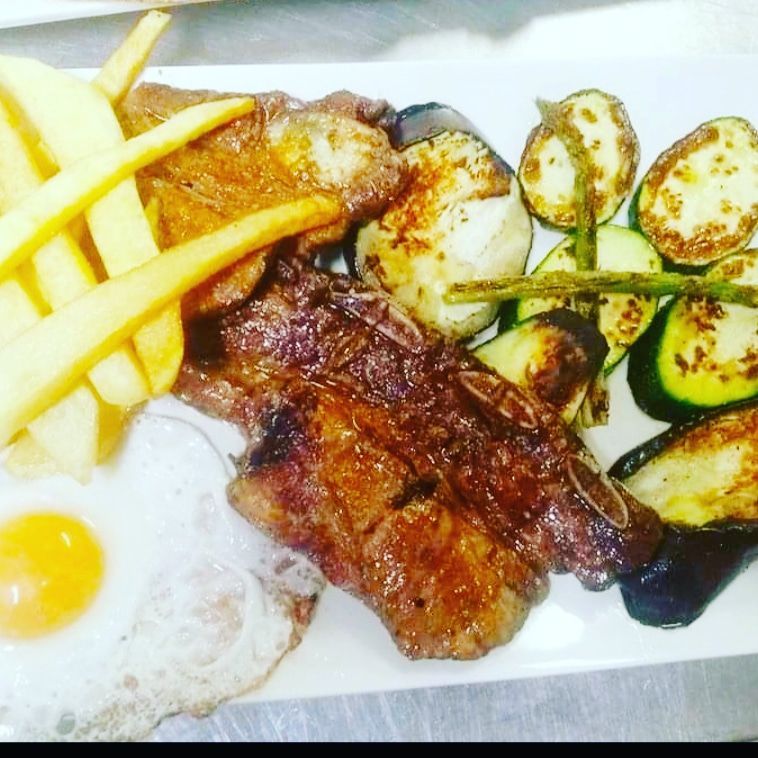 Un plato blanco cubierto con carne, huevos y verduras.