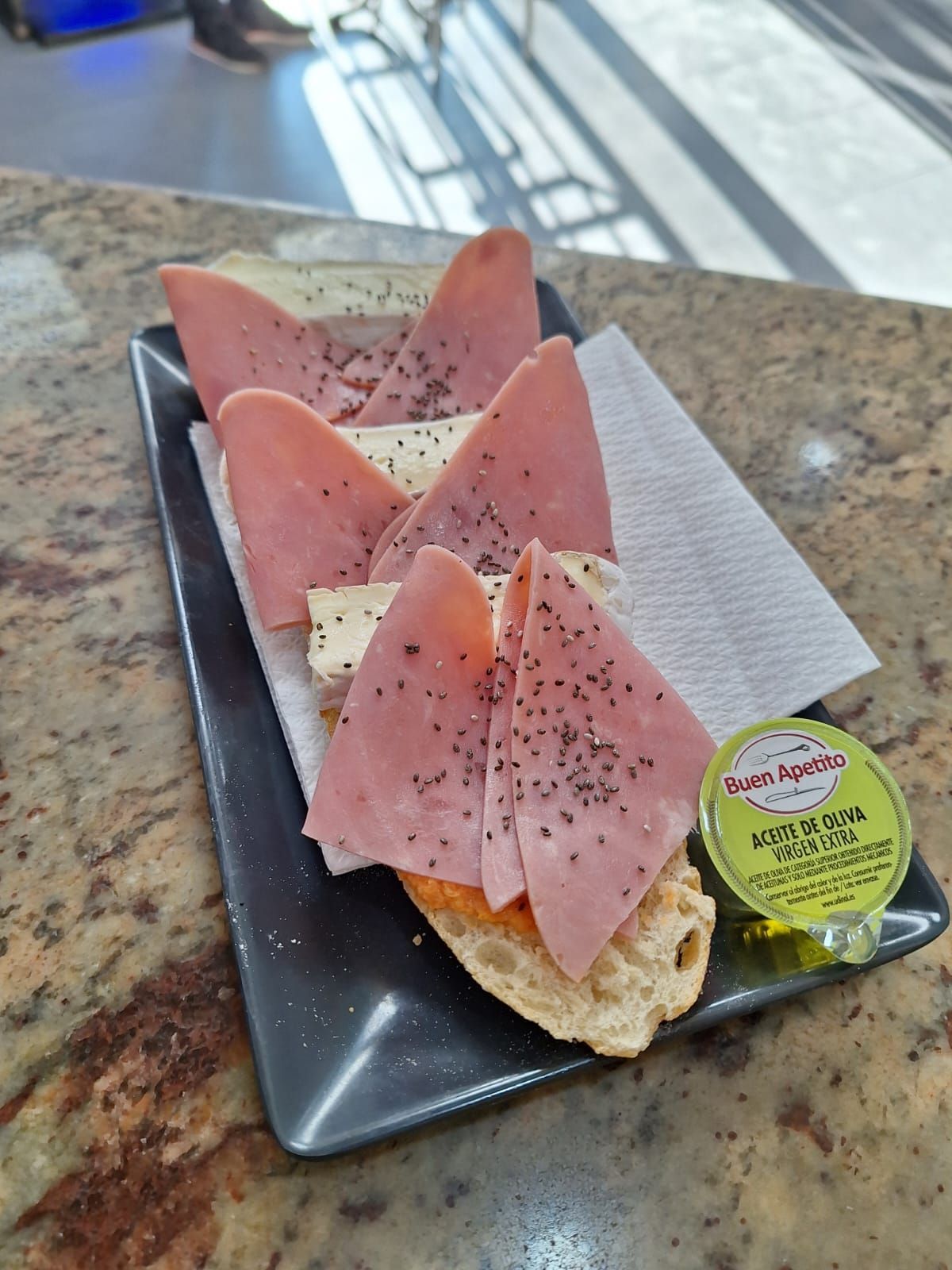 Un sándwich con jamón y queso en un plato negro.