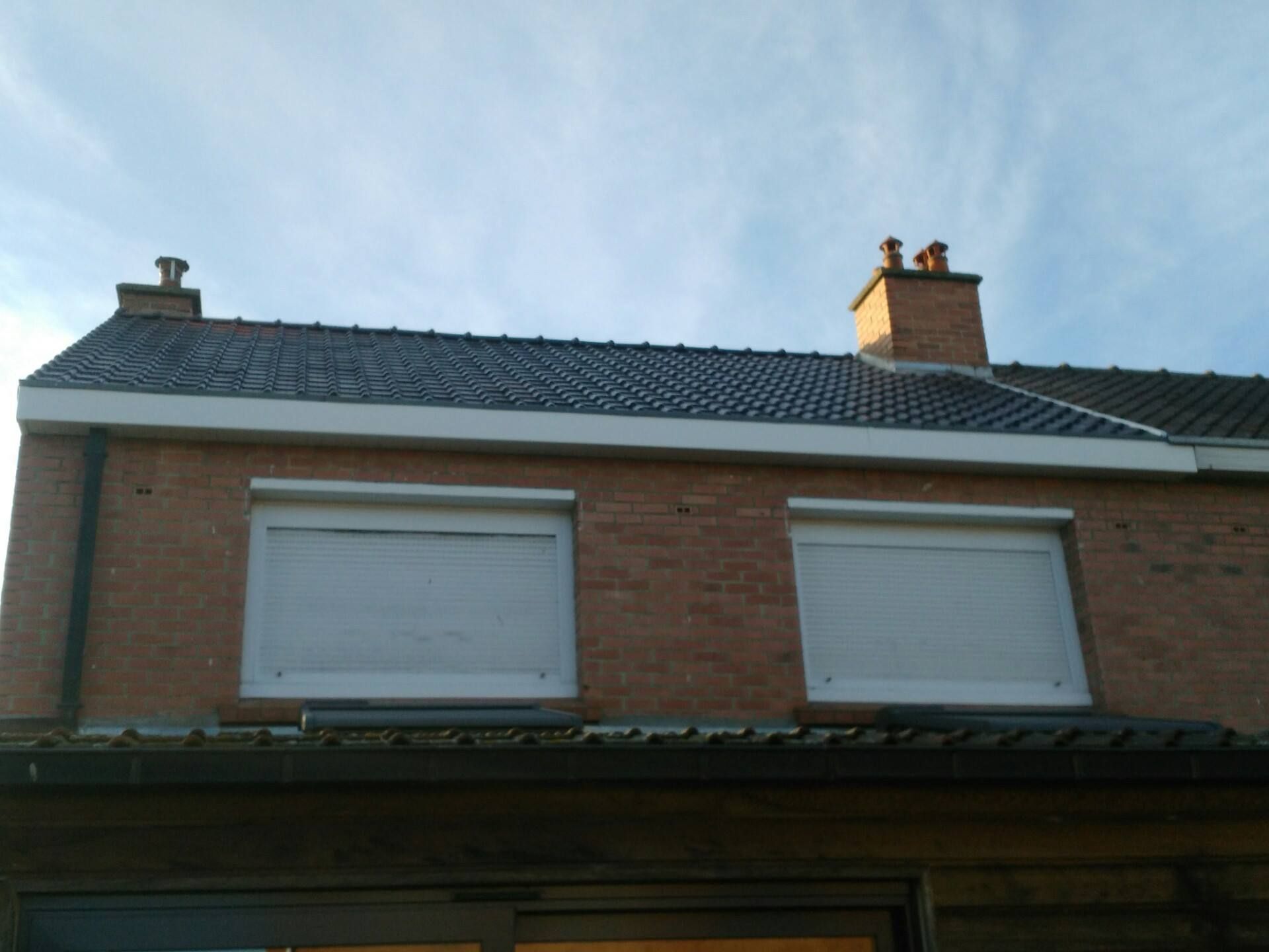 Fenêtres de maison clôturées par des volets roulants et couverture de toit neuve