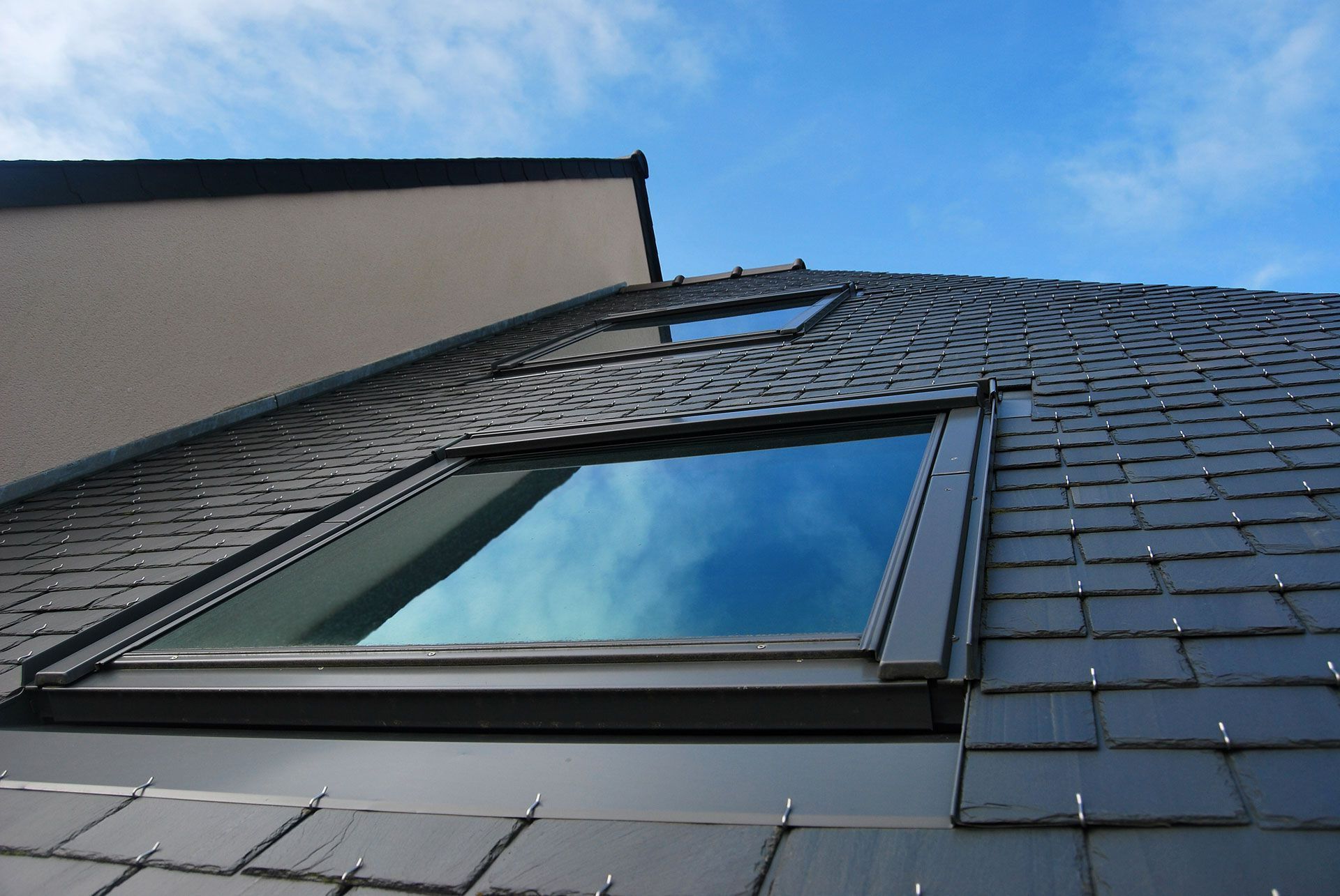 Fenêtre de toit de type Velux sur un toit composé de tuiles en ardoise