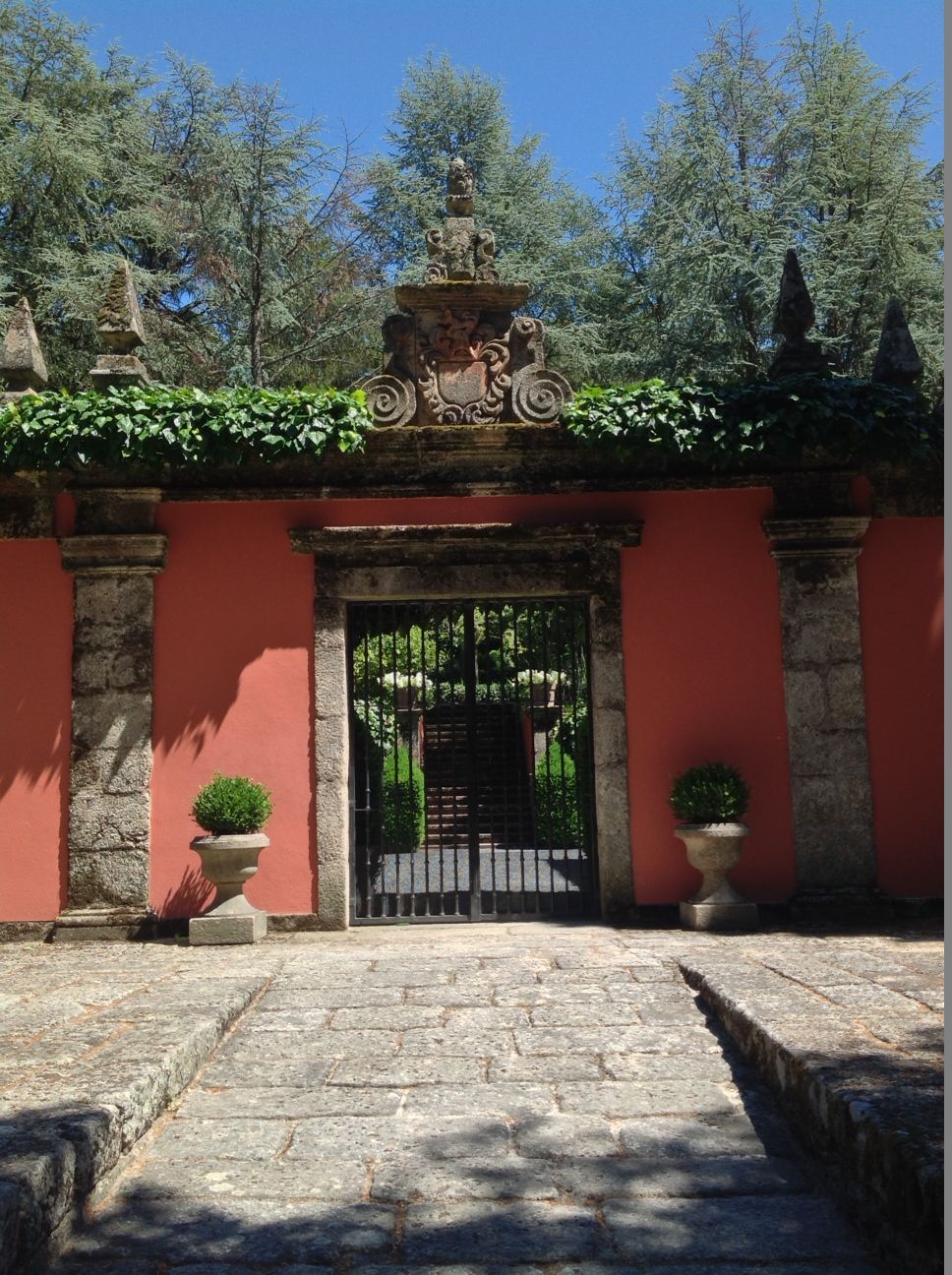 Uma passagem de pedra que leva a um portão com uma parede vermelha atrás dele