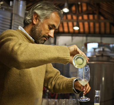 homem a encher copo com vinho branco